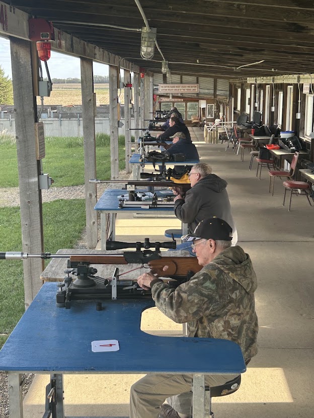 Shooters at the benches along the covered rifle line